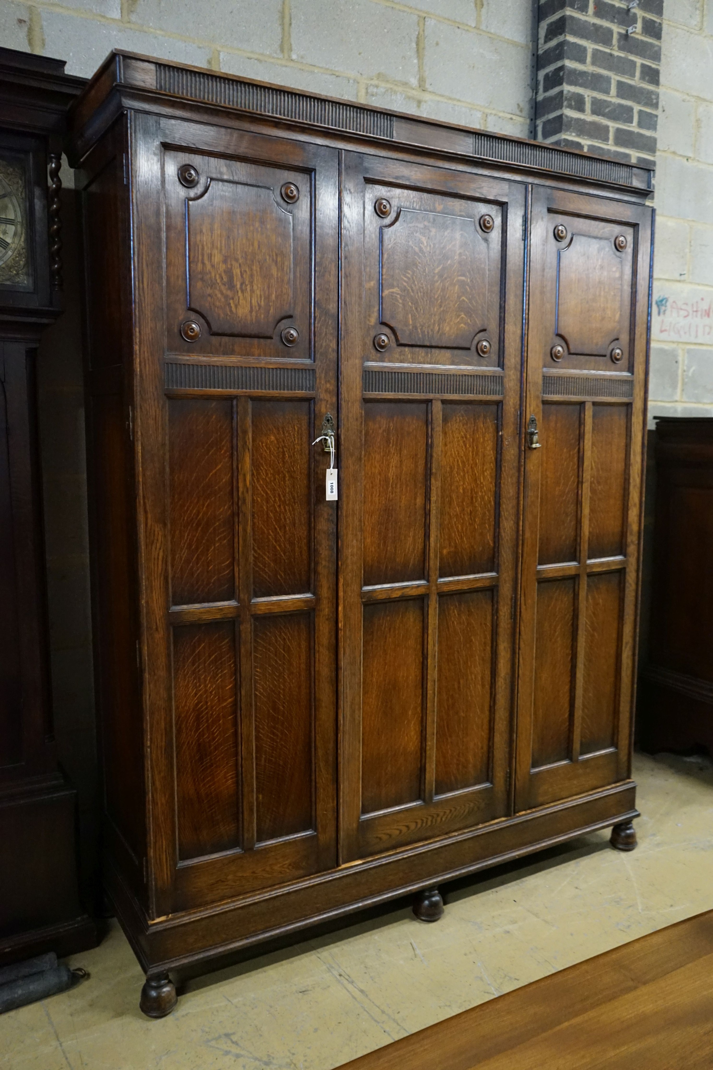 A carved and panelled oak triple wardrobe with fitted interior, length 150cm, depth 49cm, height 200cm